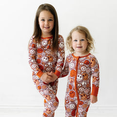Two children holding hands wearing matching Groovy Baby printed pajama sets.