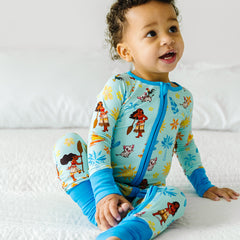 child in Little Sleepies | Disney Moana of Motunui printed zippy pajama with Pua Lovey