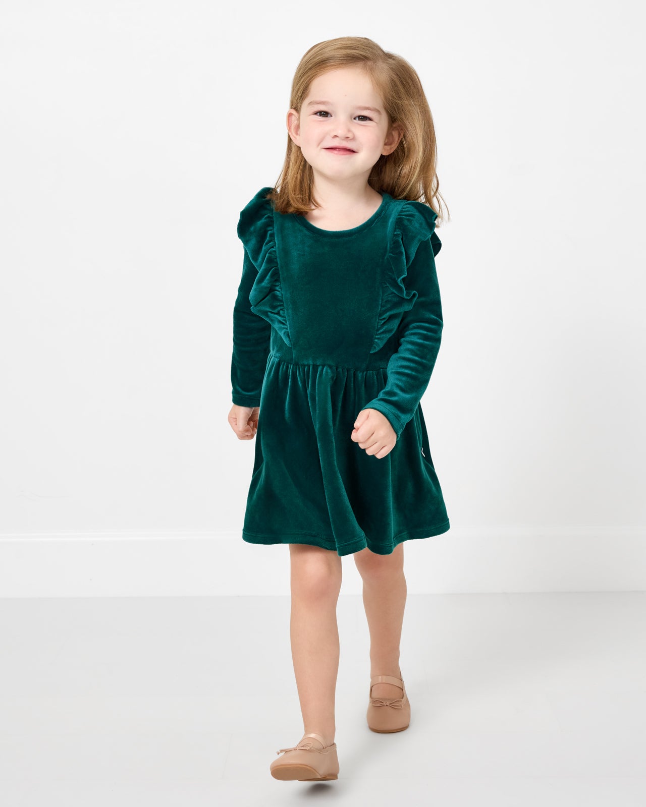 Walking child wearing the Emerald Velvet Easy Fit Flutter Dress