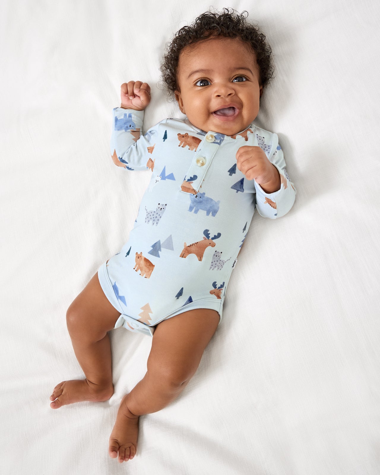 Baby on a white blanket wearing the Alpine Explorers Henley Bodysuit