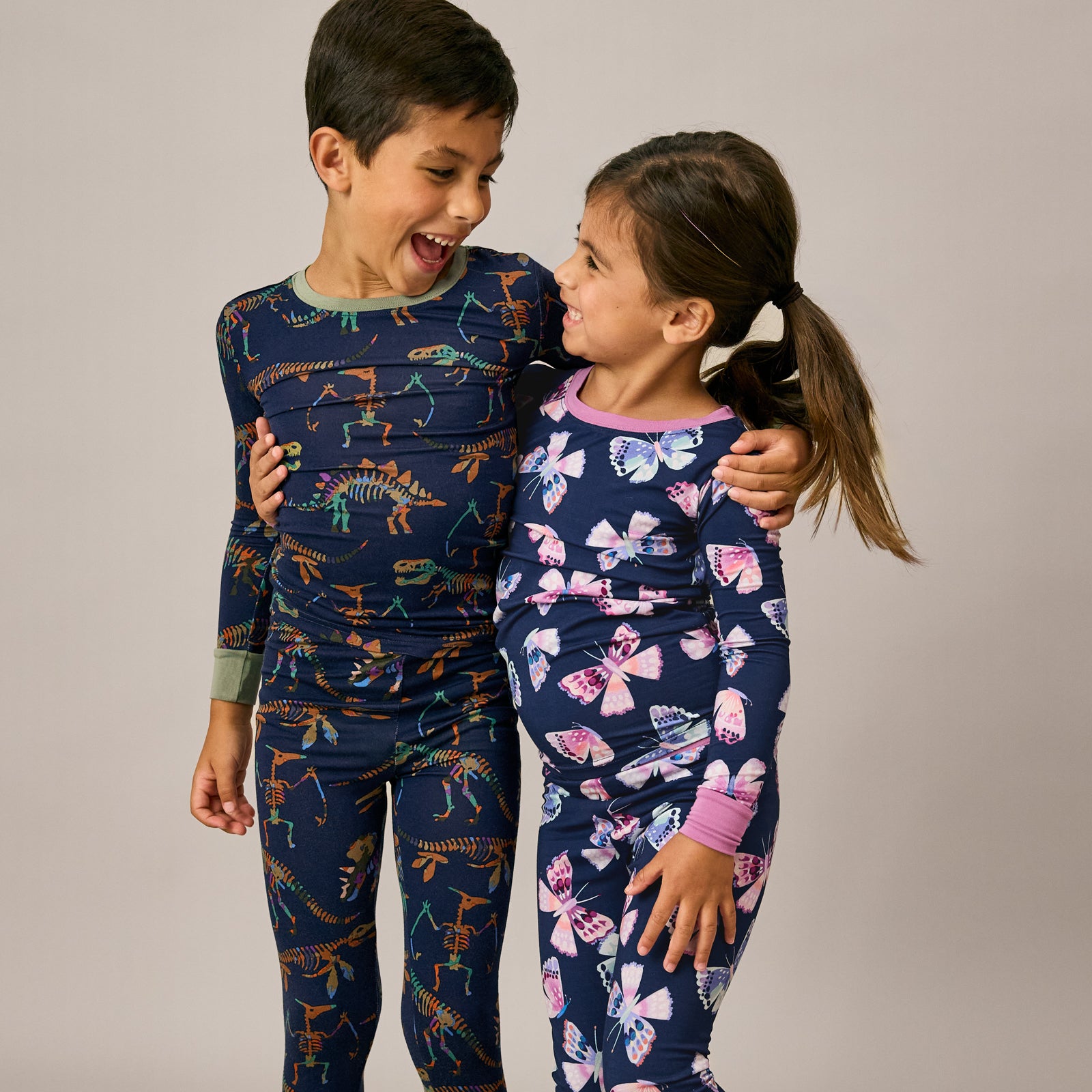Boy and girl wearing dinosaur and butterfly themed pajamas