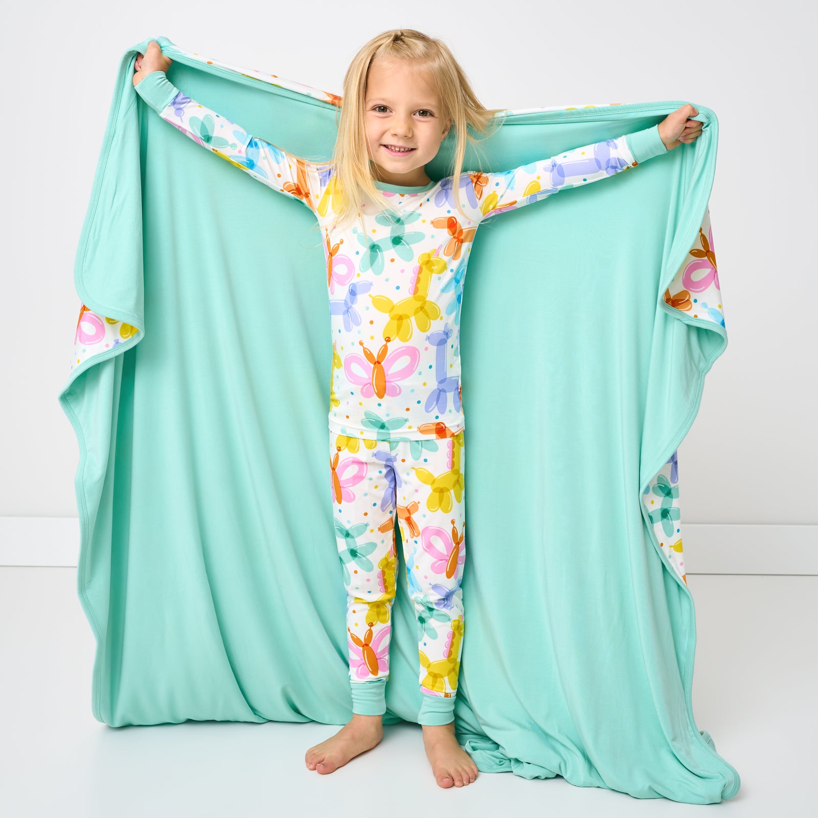 Standing child holding up the Balloon Bash Large Cloud Blanket®