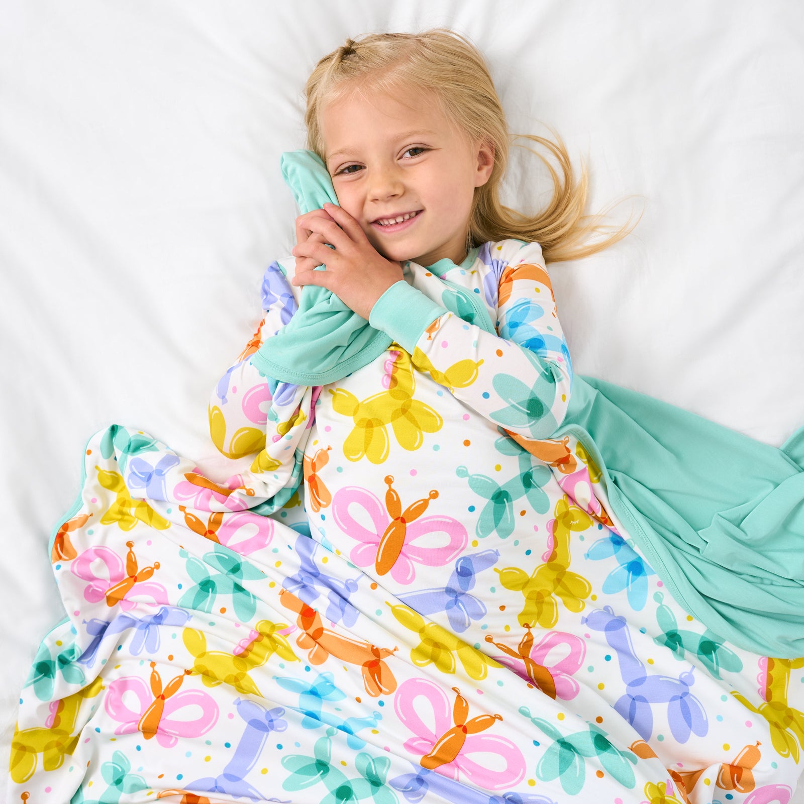 Aerial view of child snuggled in the Balloon Bash Large Cloud Blanket®
