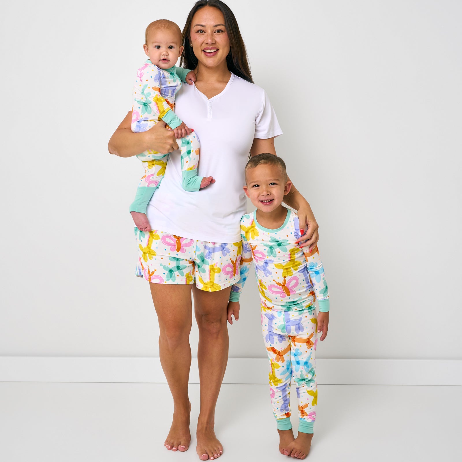 Standing mother and two children wearing matching Balloon Bash pjs