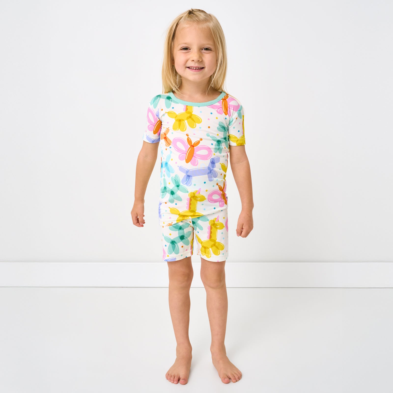 Standing child wearing the Balloon Bash Two-Piece Short Sleeve & Shorts Pajama Set