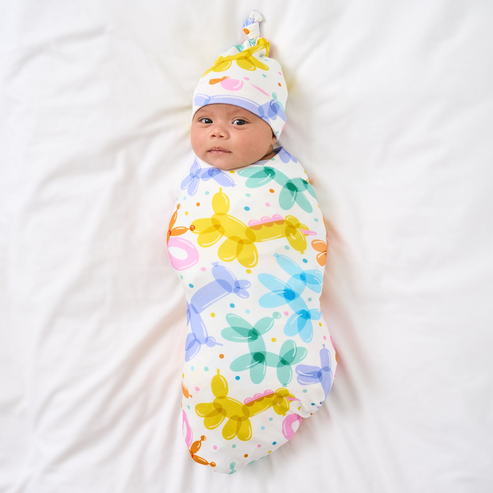 Aerial view of child wearing the Balloon Bash Swaddle & Hat Set