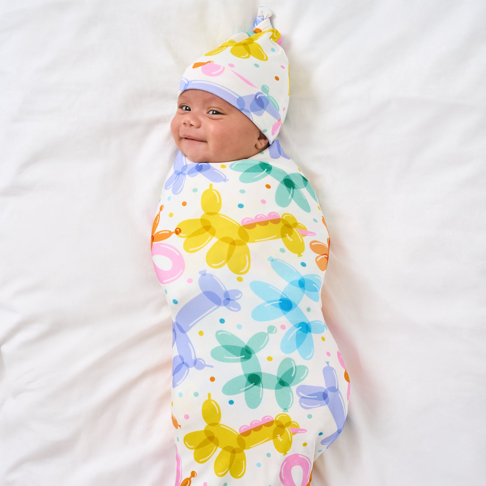Alternate aerial view of child wearing the Balloon Bash Swaddle & Hat Set