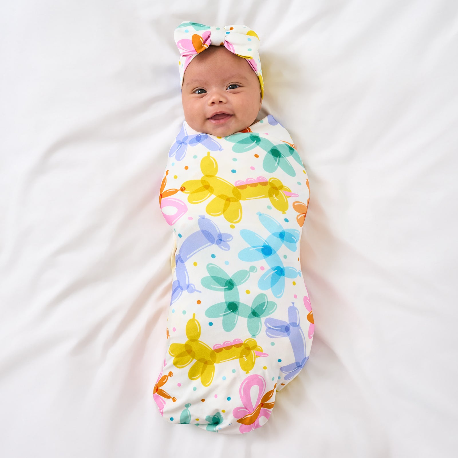 Aerial view of child wearing the Balloon Bash Swaddle & Luxe Bow Headband Set