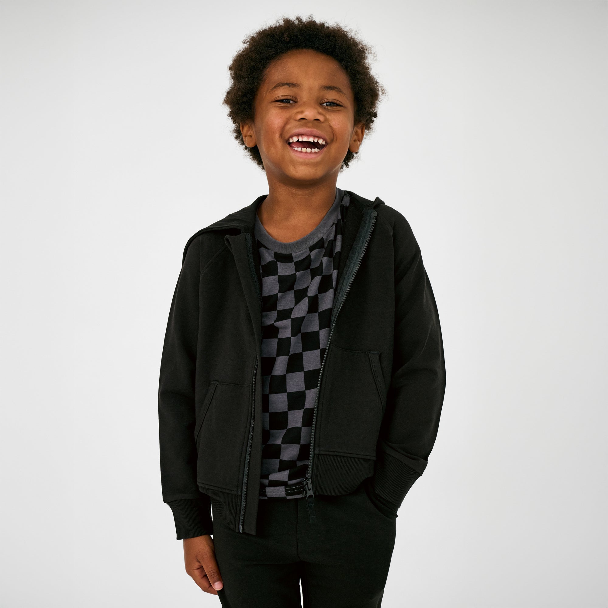 Child wearing the Black Zip Hoodie layered over a monochrome checks tee