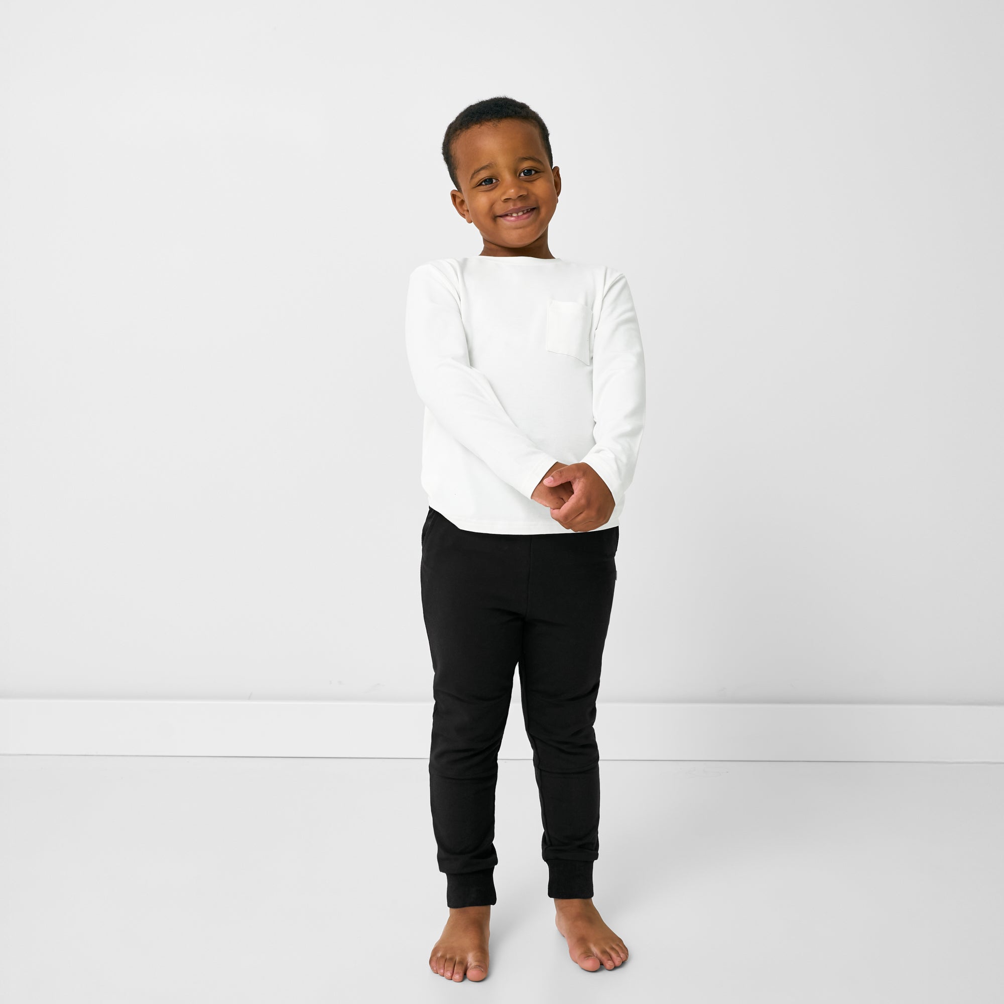 Standing child wearing the Black Jogger with a white long sleeve tee