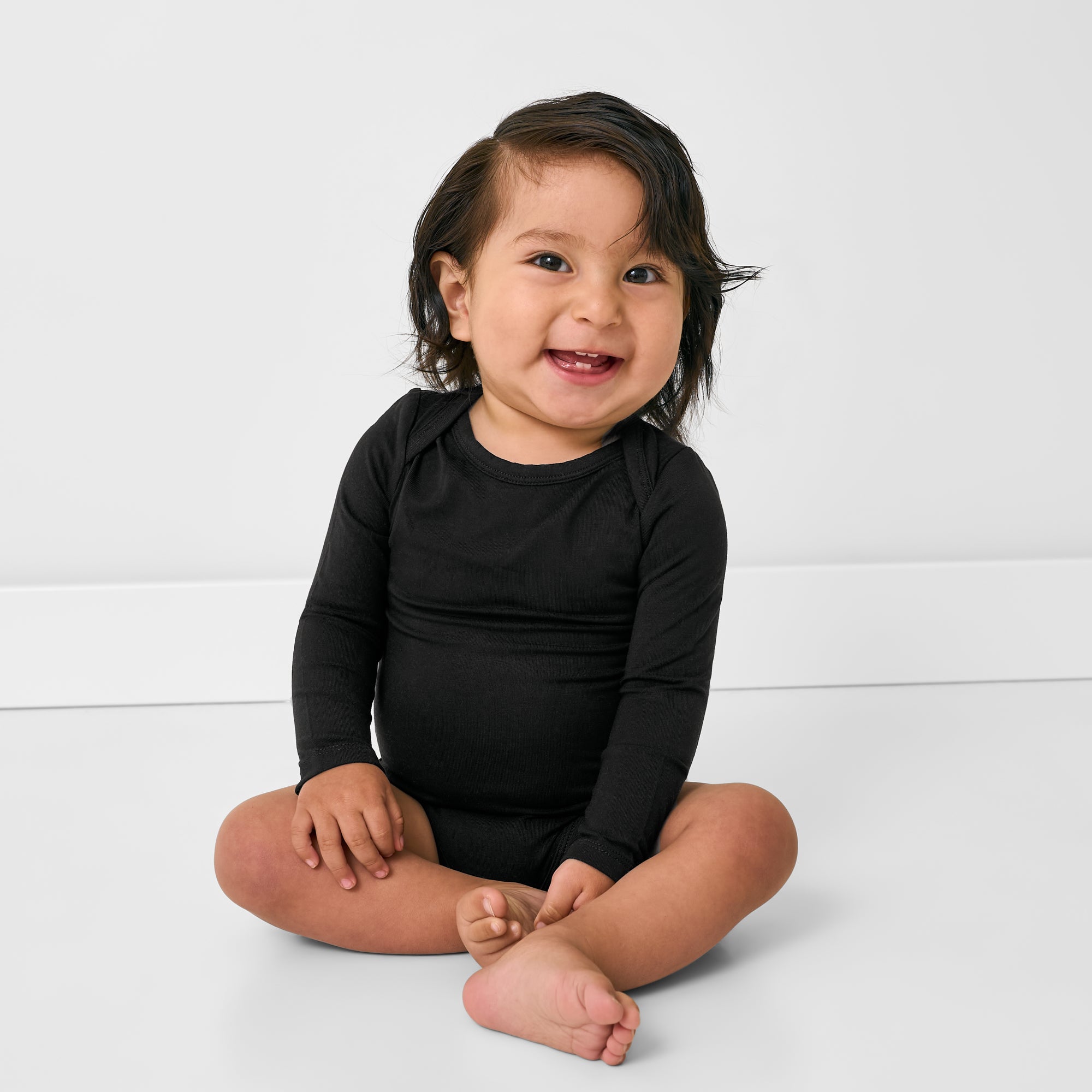 Sitting baby wearing the Black Long Sleeve Bodysuit