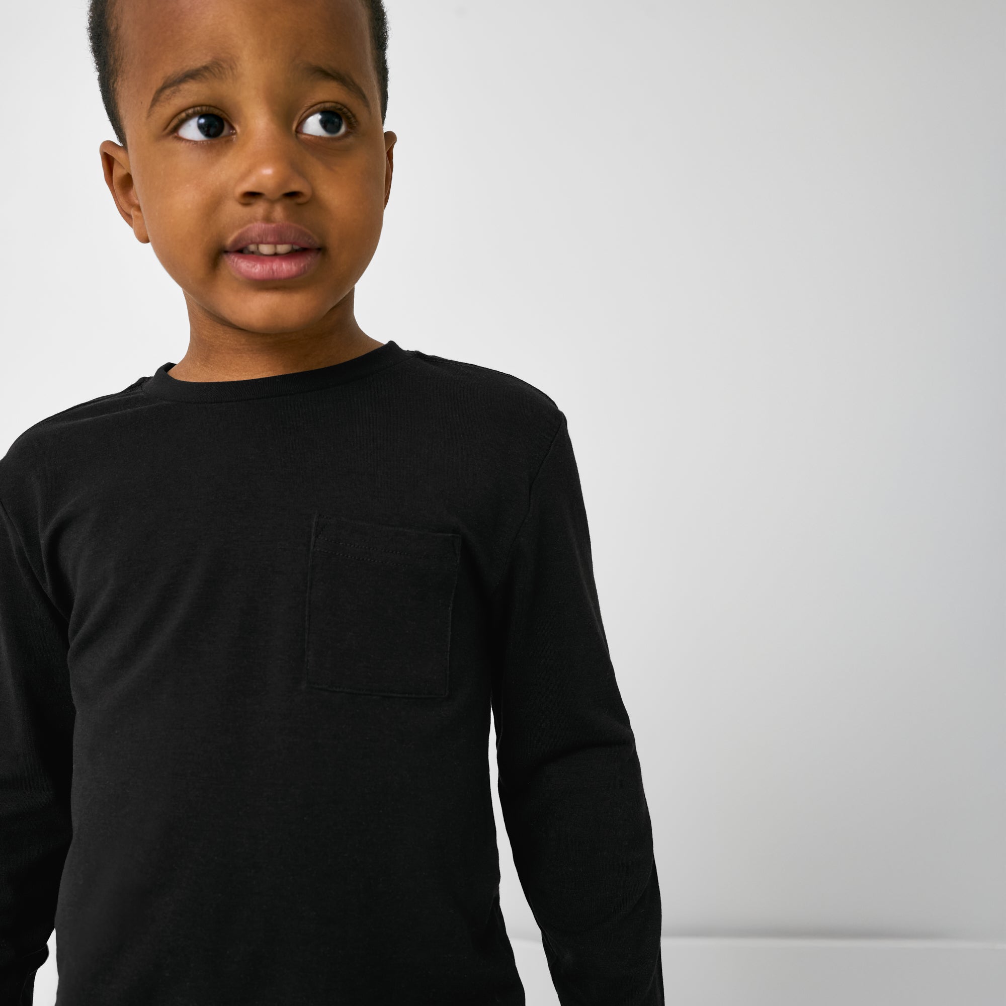 Close up of child wearing the Black Long Sleeve Relaxed Pocket Tee