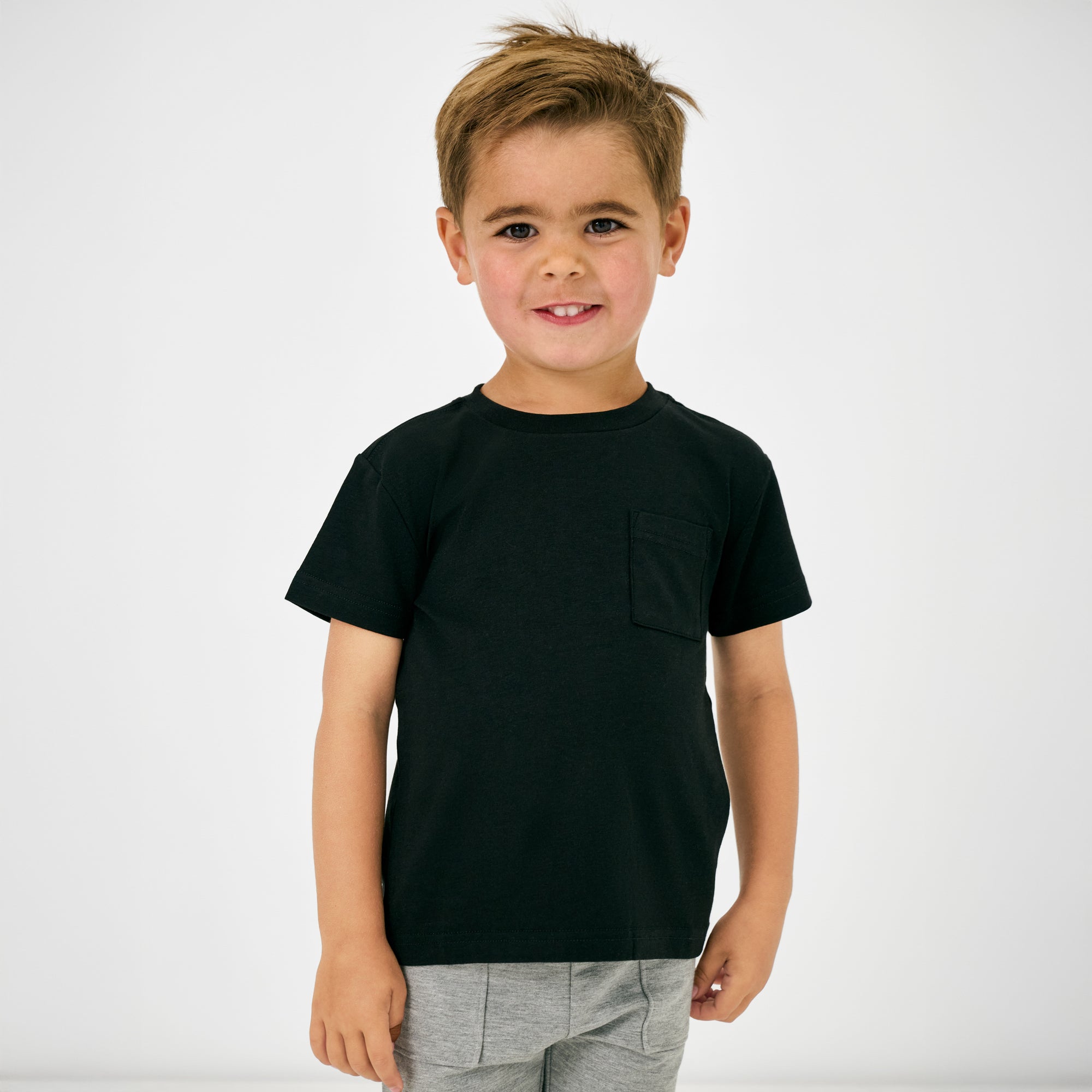 Standing child wearing the Black Short Sleeve Relaxed Pocket Tee