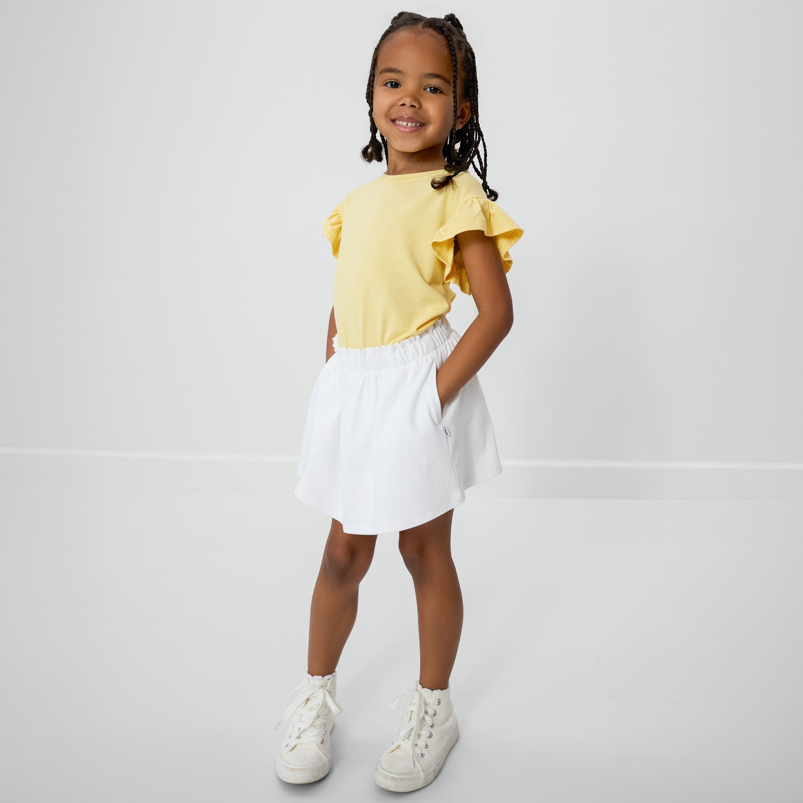 Posing child wearing the Bright White Denim Skort with the Lemon Twist flutter tee