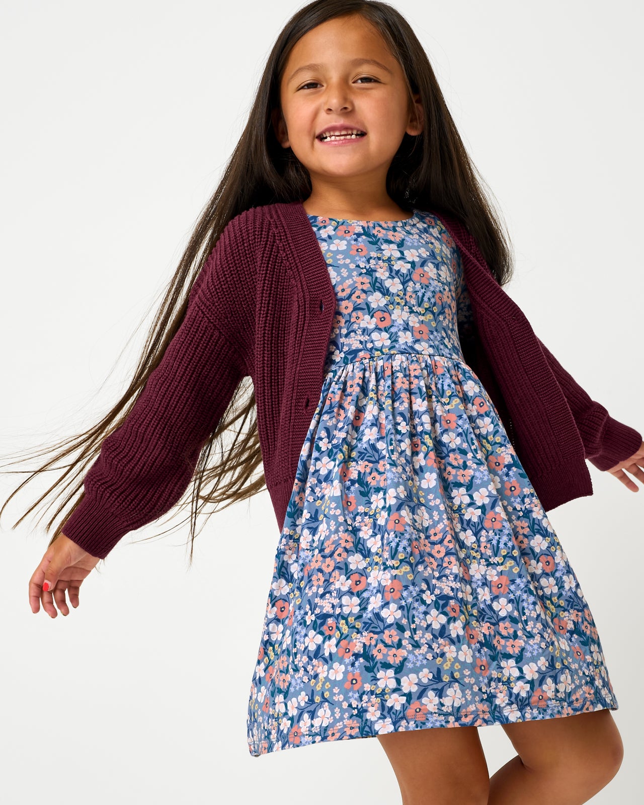 Girl wearing the Classic Burgundy Cropped Sweater layered over a floral dress