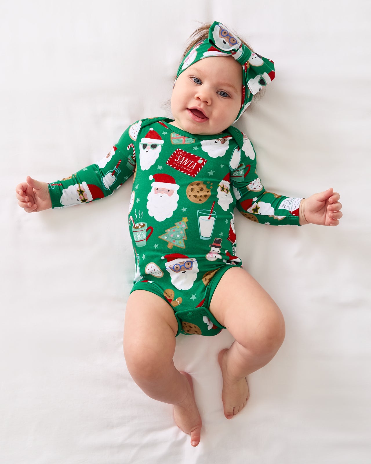 Aerial view of baby wearing the Cookies for Santa Bodysuit with a matching luxe bow headband