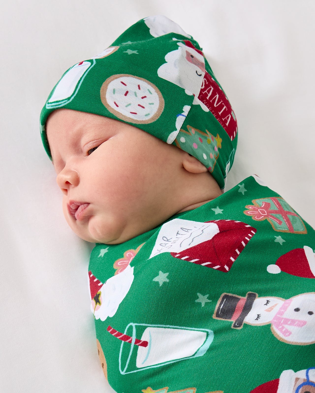 Close up of baby wearing the Cookies for Santa Swaddle & Hat Set