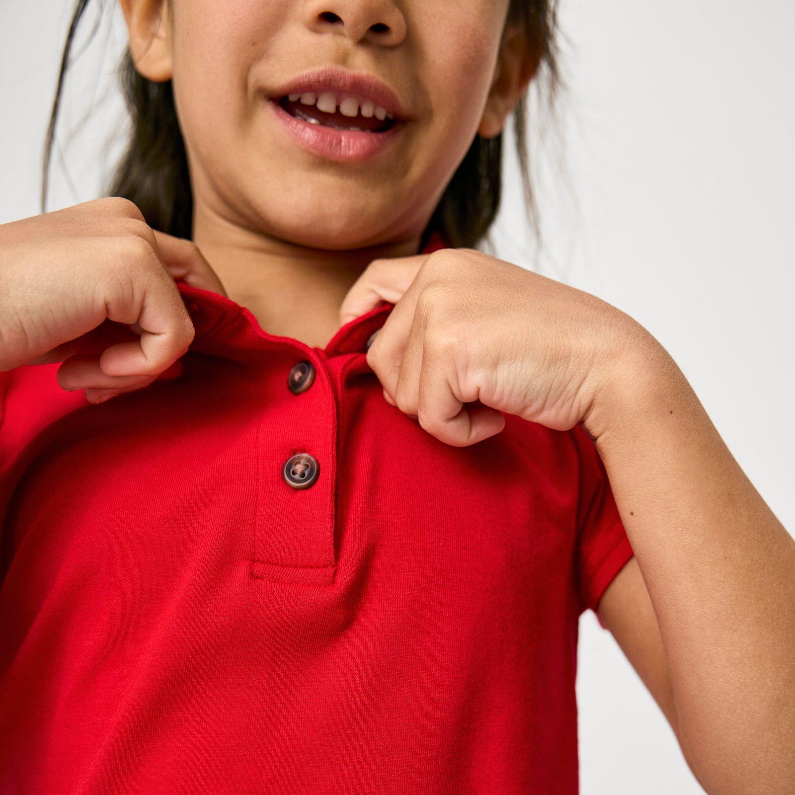 Close up of child adjusting the collar on the Candy Red Puff Sleeve Polo
