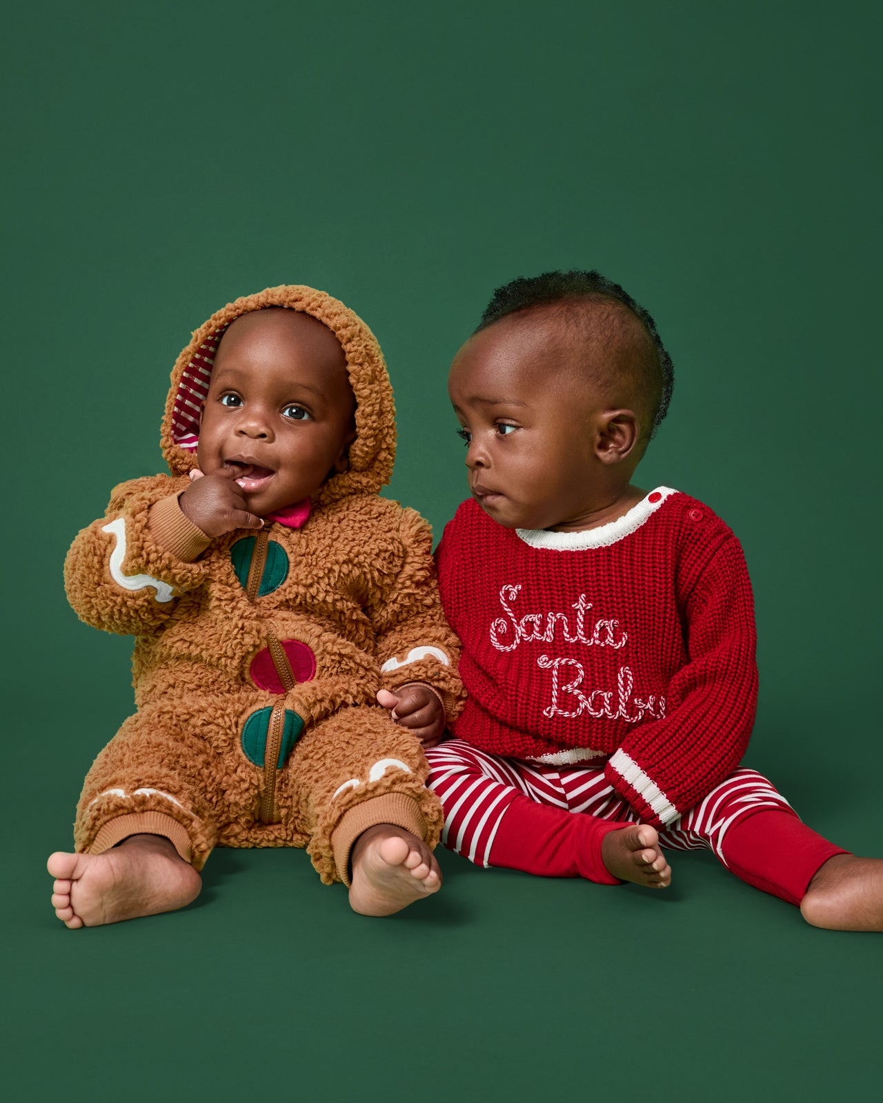 Two baby wearing Holiday Collection styles on a green background