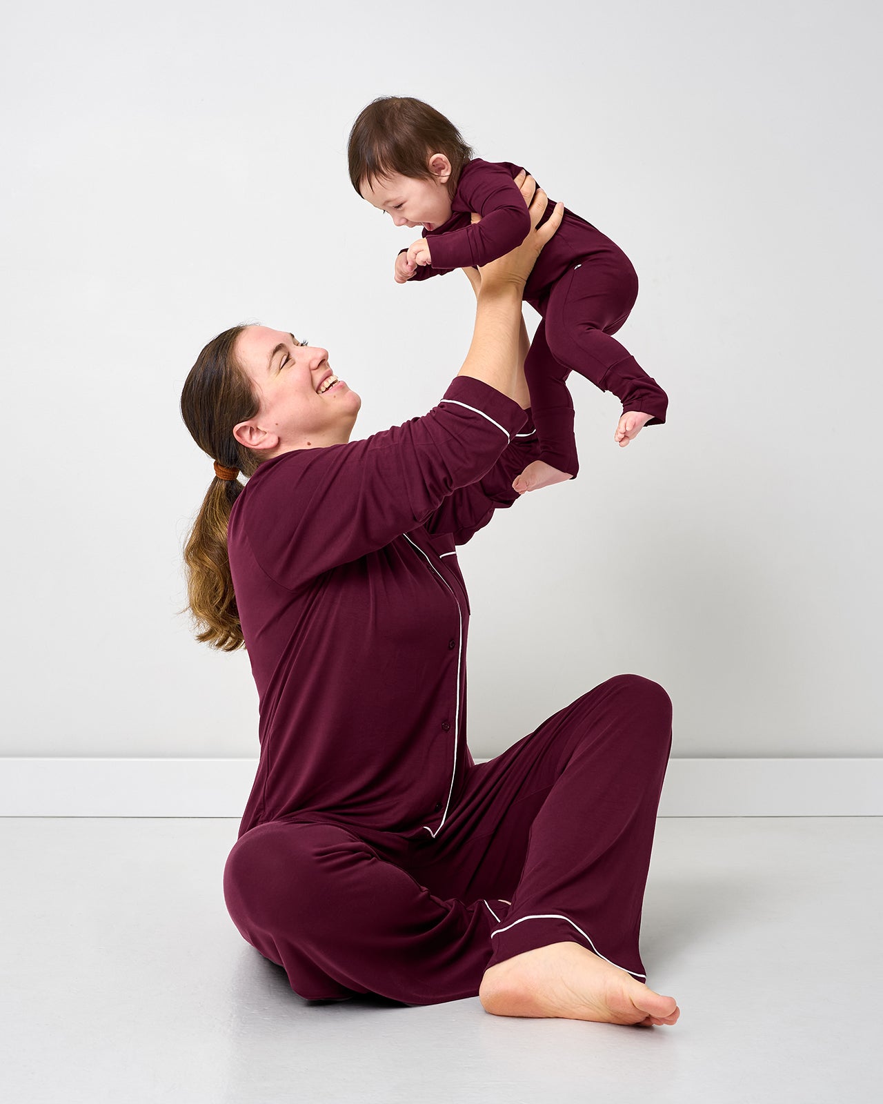 Mother holding up baby wearing matching Classic Burgundy pjs