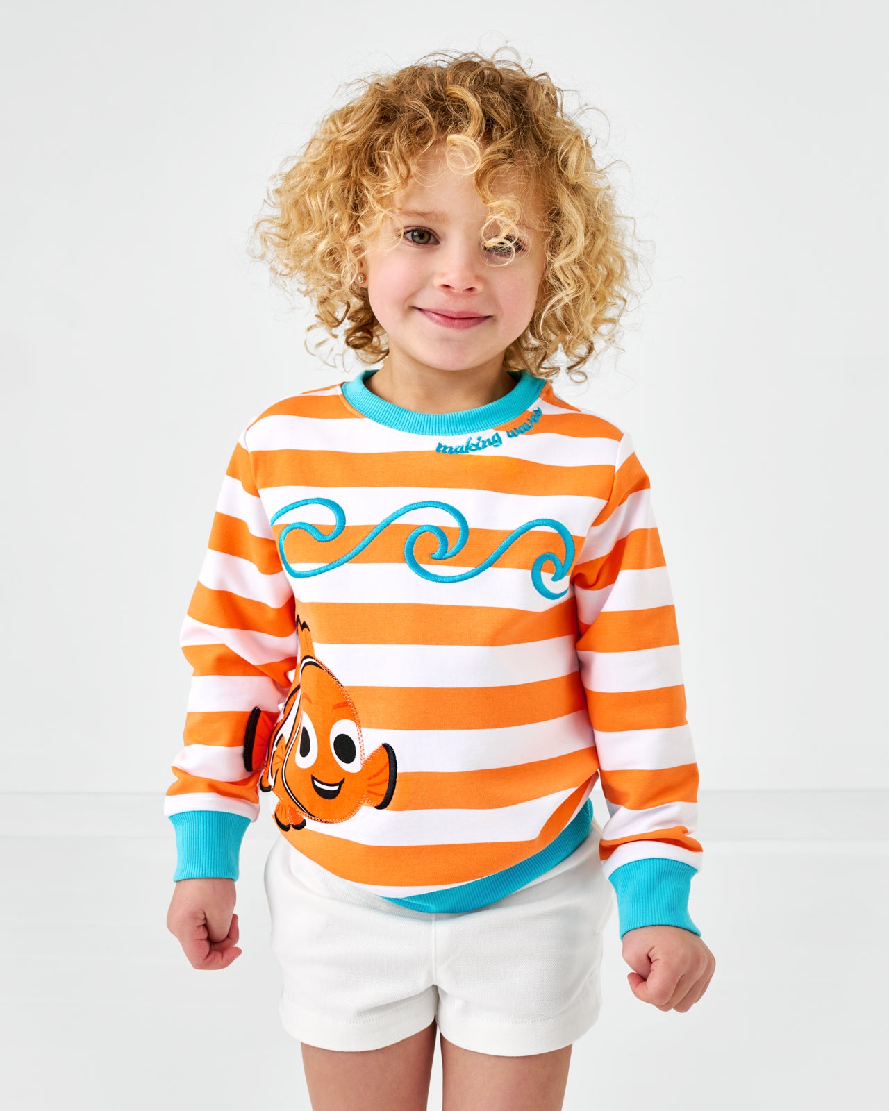 Child wearing the Disney Nemo Crewneck Sweatshirt with bright white denim shorts