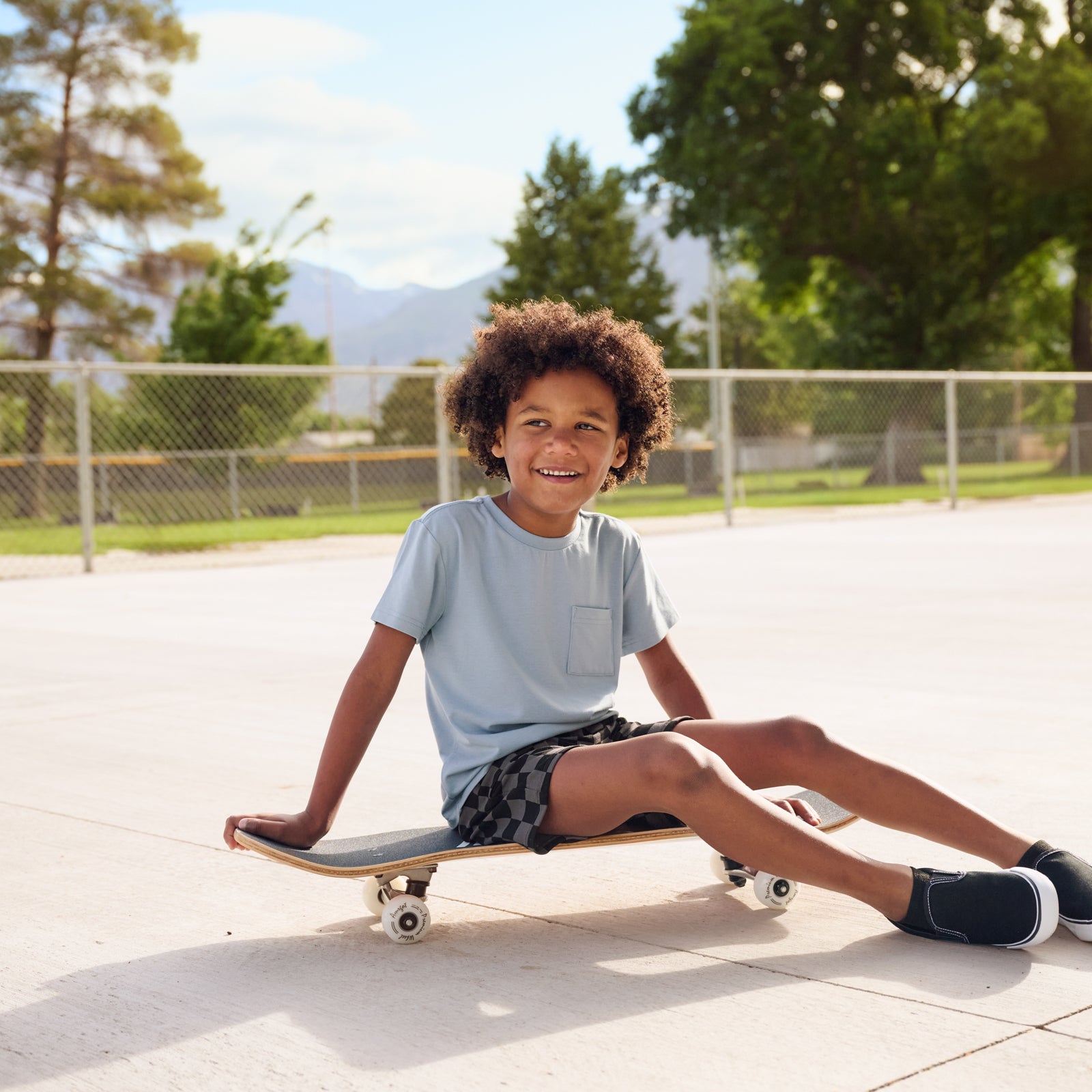 Boy at the skate park wearing the Monochrome Checks Shorts with a fog blue relaxed tee