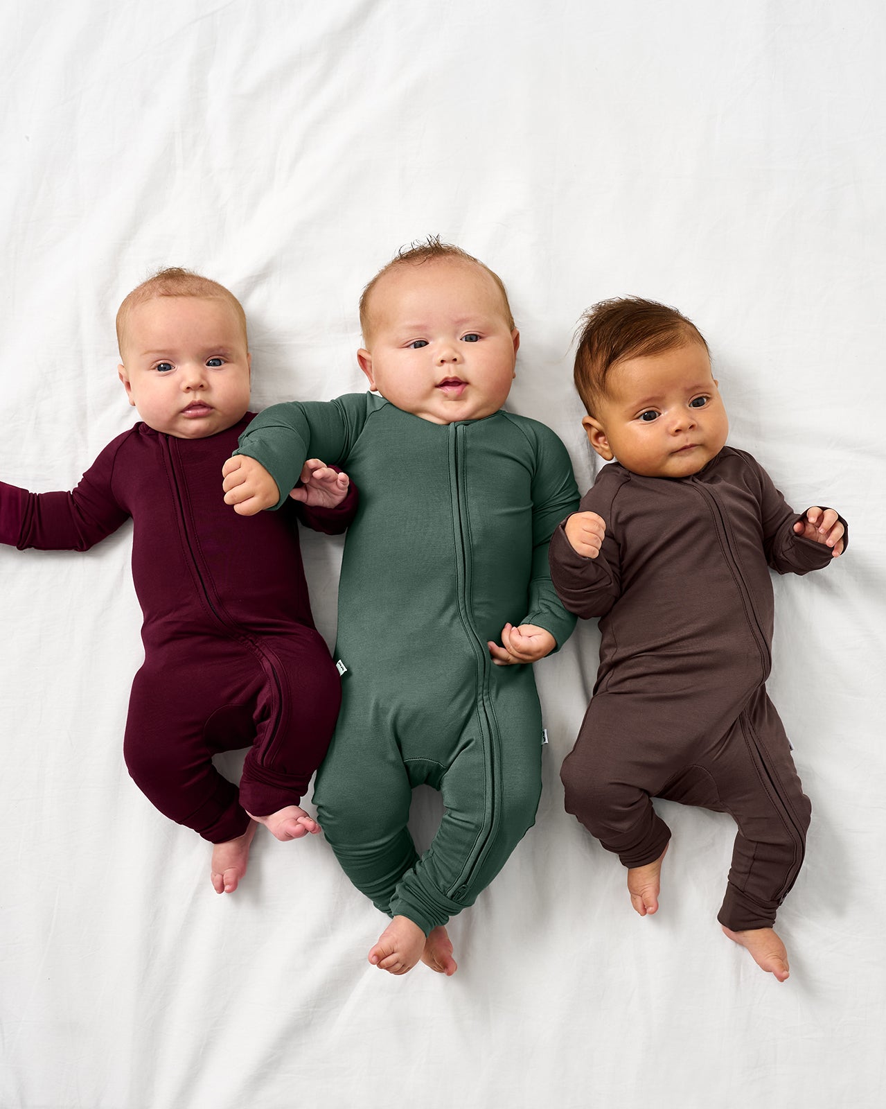 Three babies wearing zippies from the Fall Solids color way