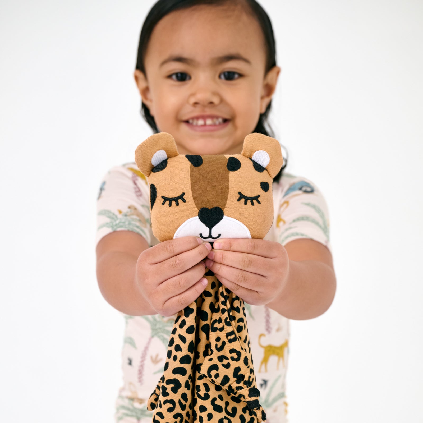 Child holding up the Dash the Leopard Sleepyhead Lovey wearing Wild Escape pajamas