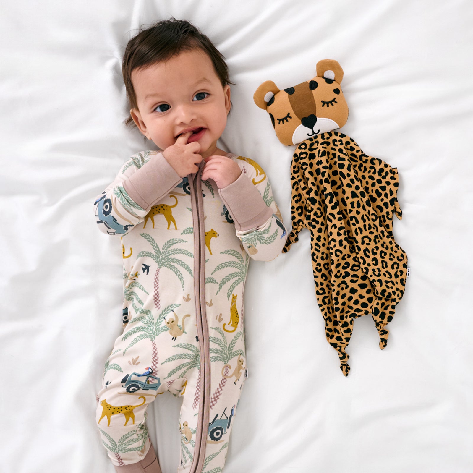 Aerial view of child laying with the Dash the Leopard Sleepyhead Lovey