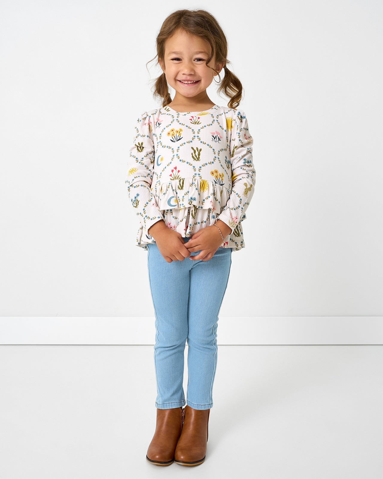 Girl wearing the Desert Meadow Ribbed Tiered Peplum Top with denim jeggings