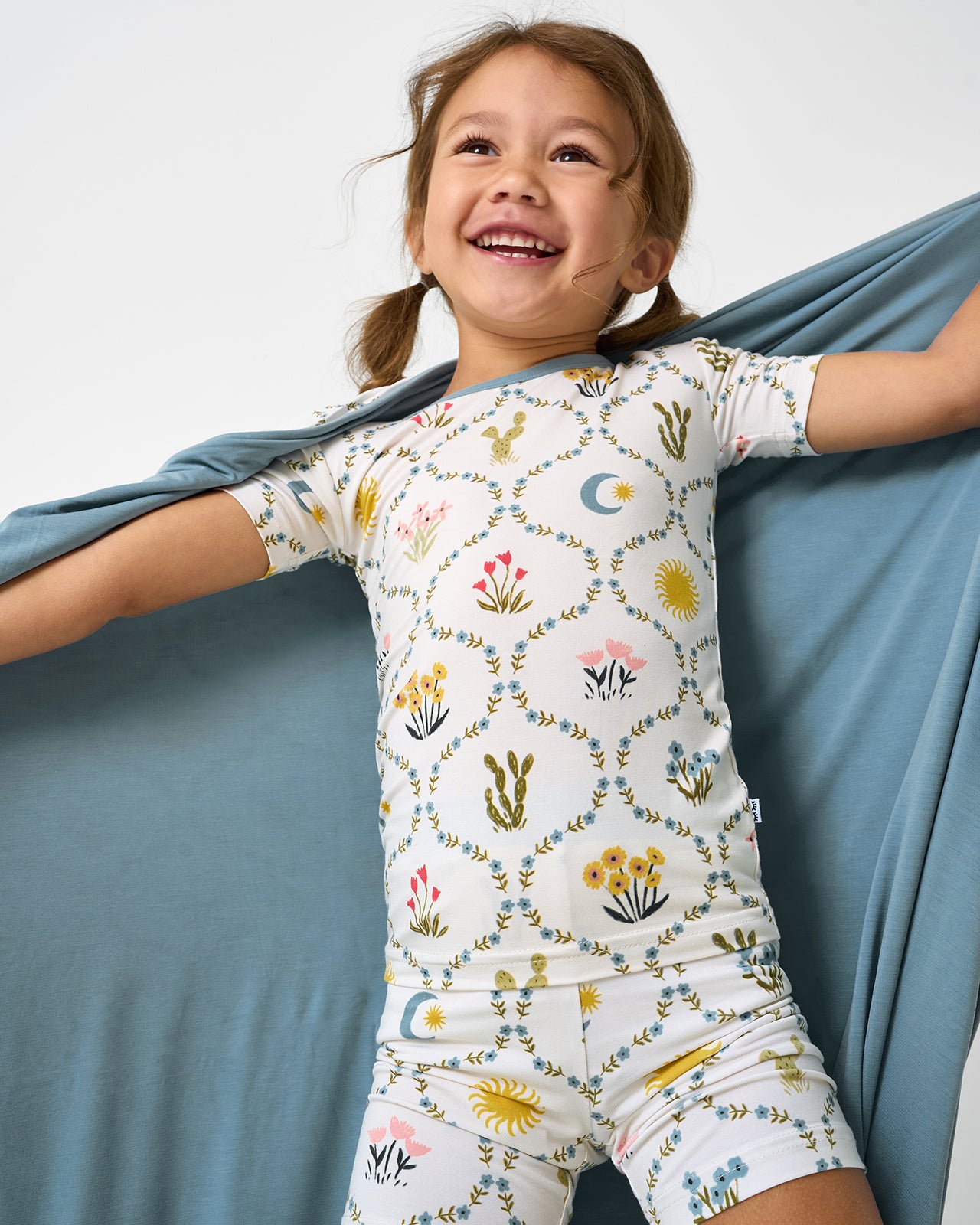 Girl holding up the Desert Meadow Large Cloud Blanket® showing the solid blue side