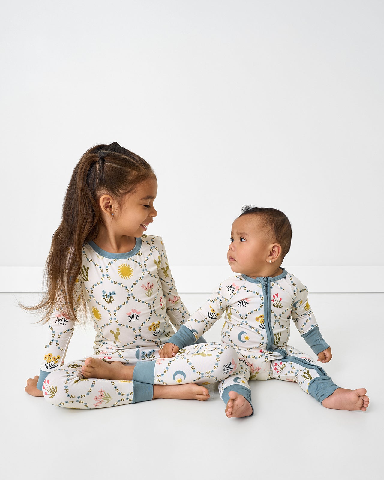 Two siblings wearing matching Desert Meadow pajamas