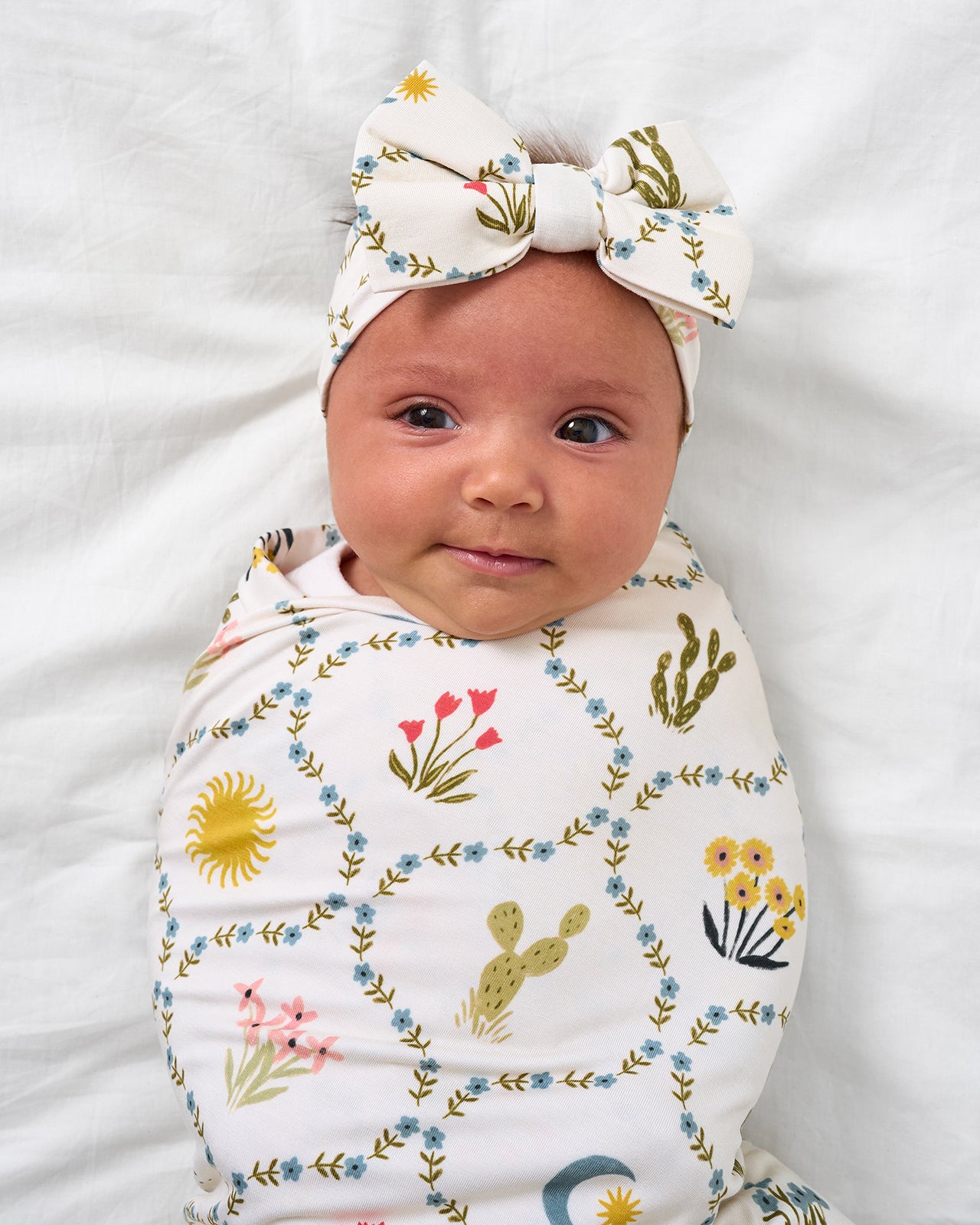 Close up of baby wearing the Desert Meadow Swaddle & Luxe Bow Headband Set