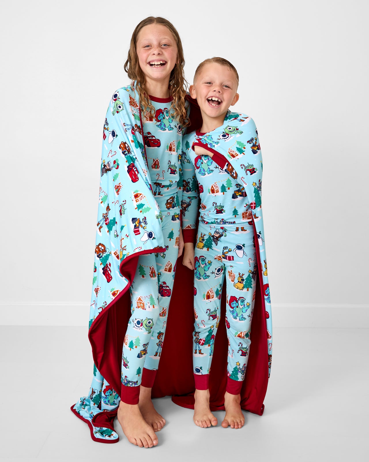 Two kids wrapped in the Disney & Pixar Christmas Village Large Cloud Blanket®