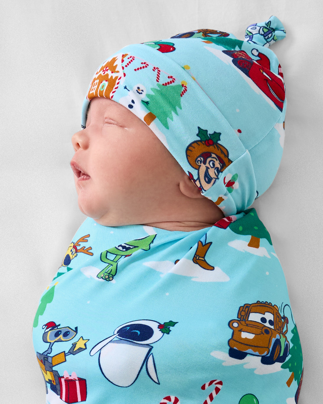 Close up of baby wearing the Disney & Pixar Christmas Village Swaddle & Hat Set