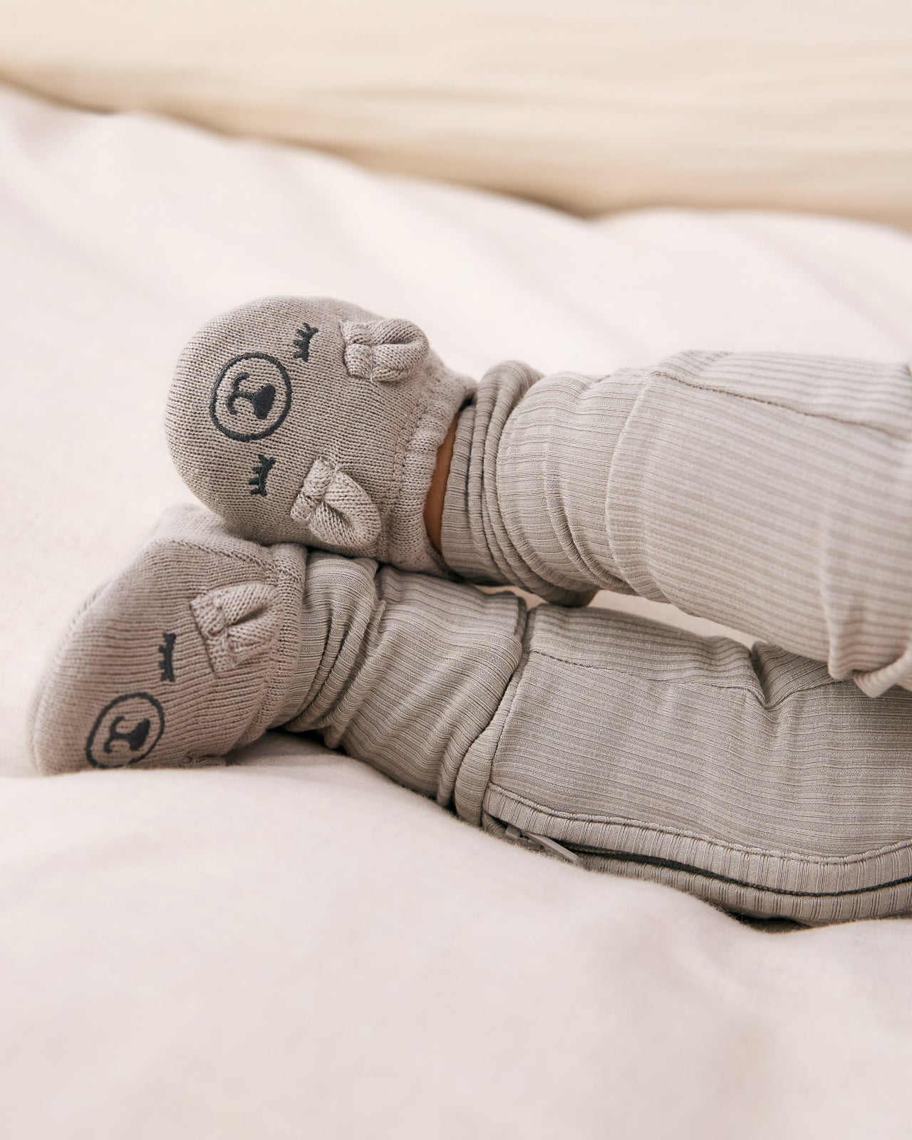 Baby wearing the Dove Gray Bear Booties on a white blanket