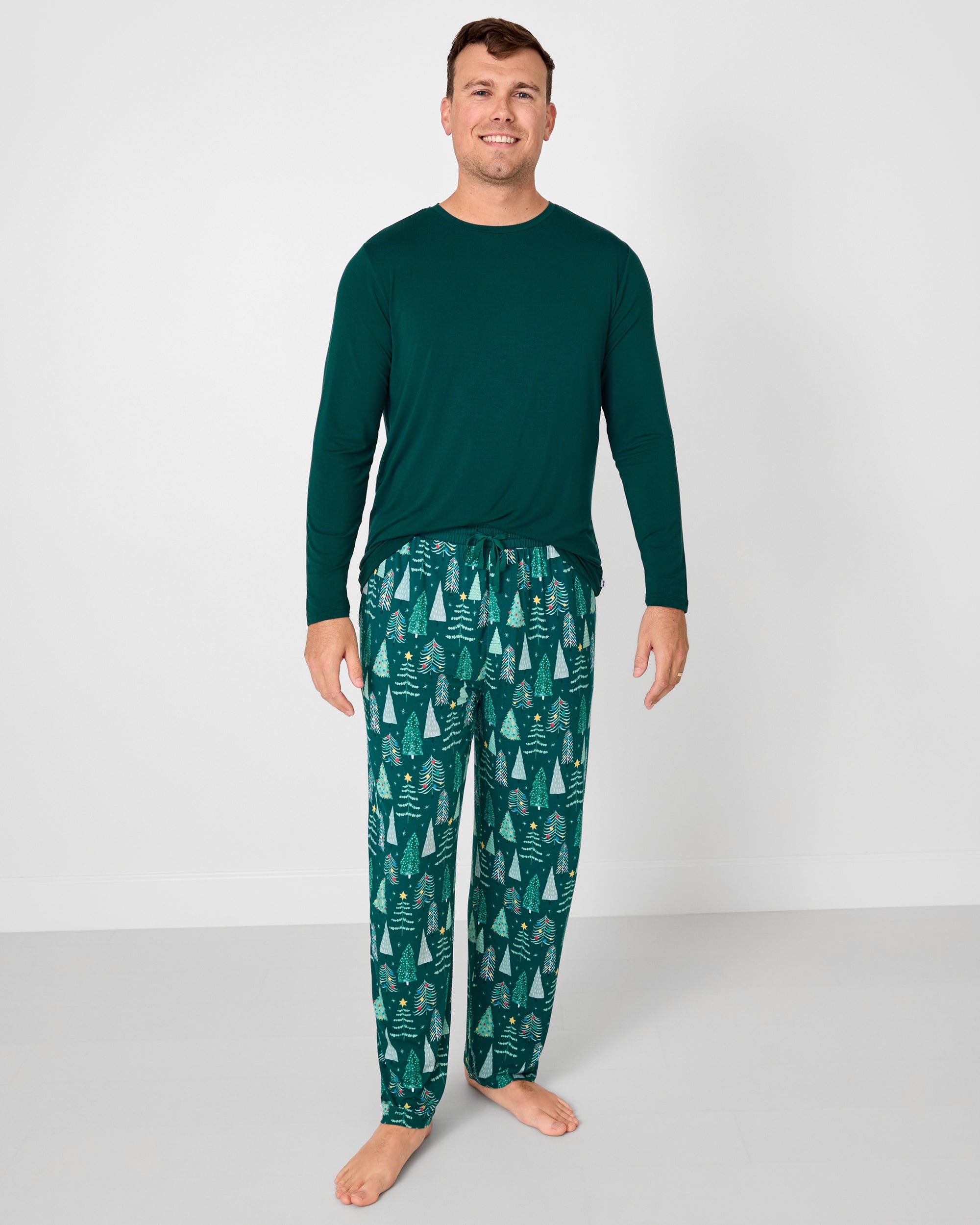 Man wearing the Emerald Men's Long Sleeve Pajama Top with Twinkling Trees holiday pajama pants