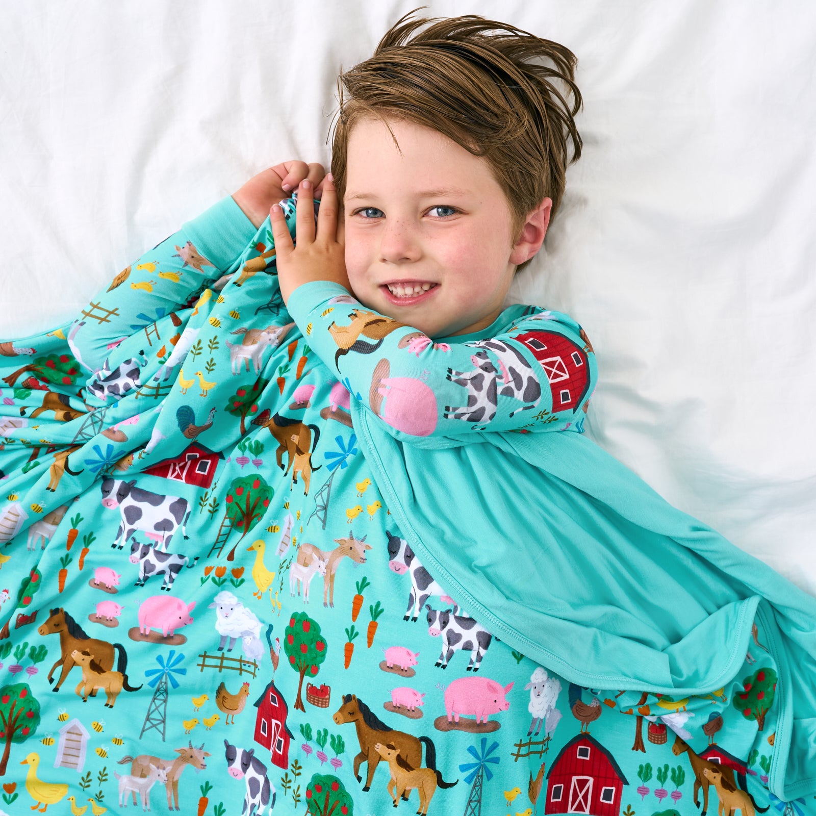 Aerial view of child wearing the Turquoise Farm Fam Large Cloud Blanket®