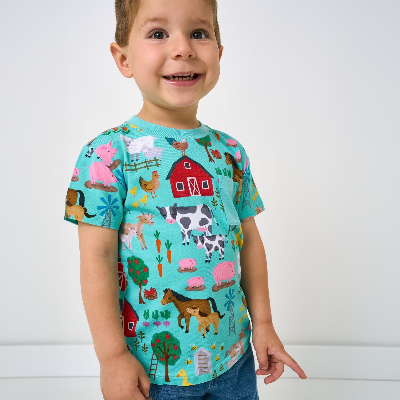 Close up of standing child wearing the Turquoise Farm Fam Relaxed Pocket Tee