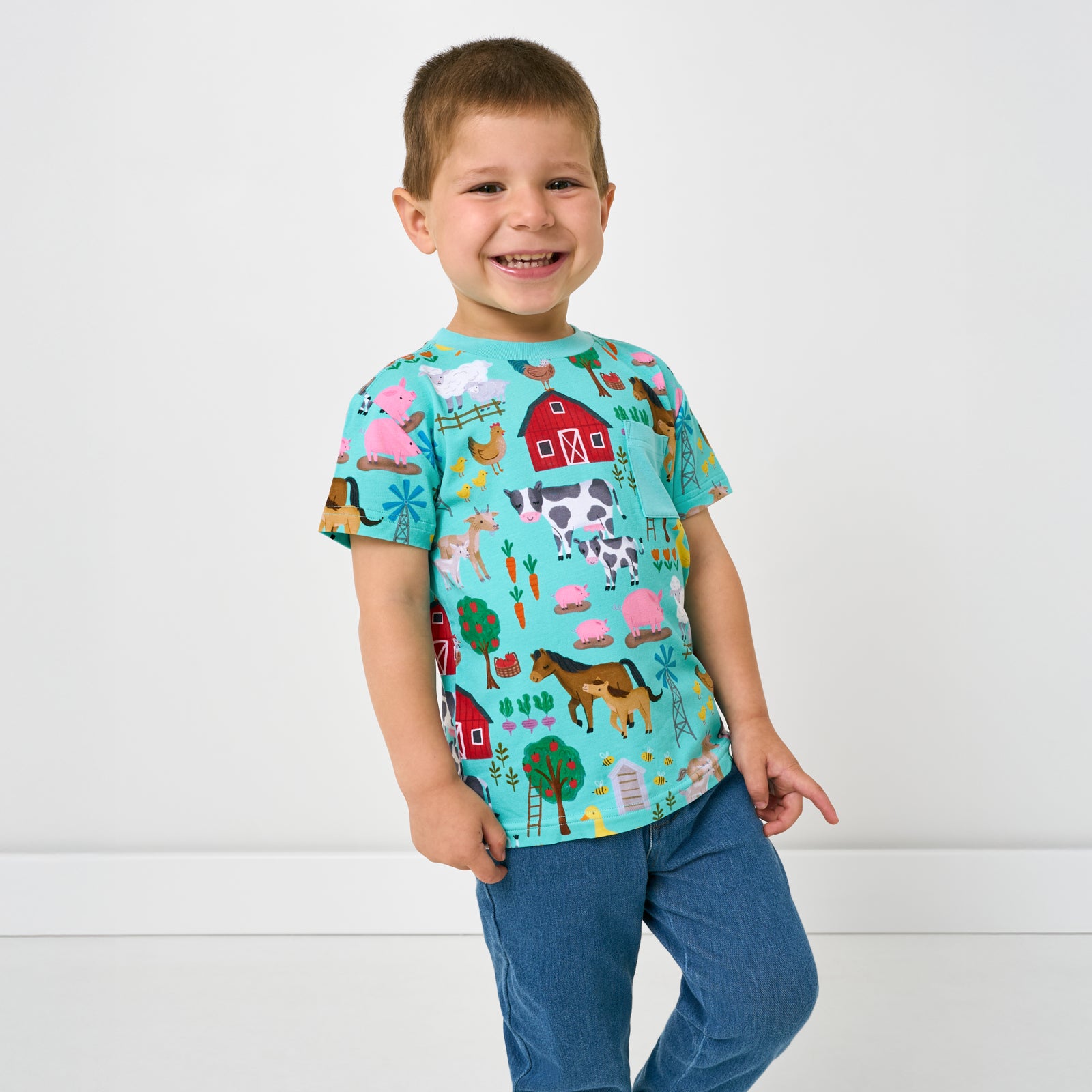 Walking child wearing the Turquoise Farm Fam Relaxed Pocket Tee with denim joggers