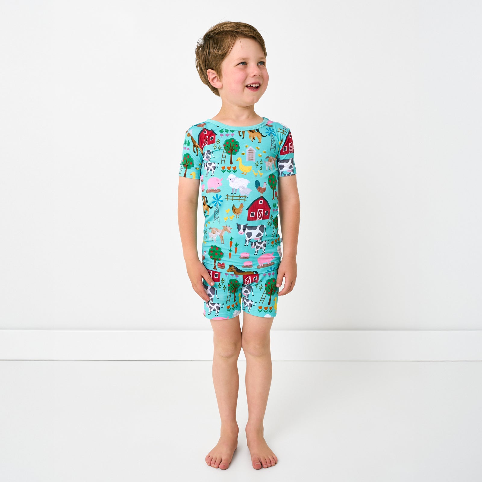 Standing child wearing the Turquoise Farm Fam Two-Piece Short Sleeve & Shorts Pajama Set