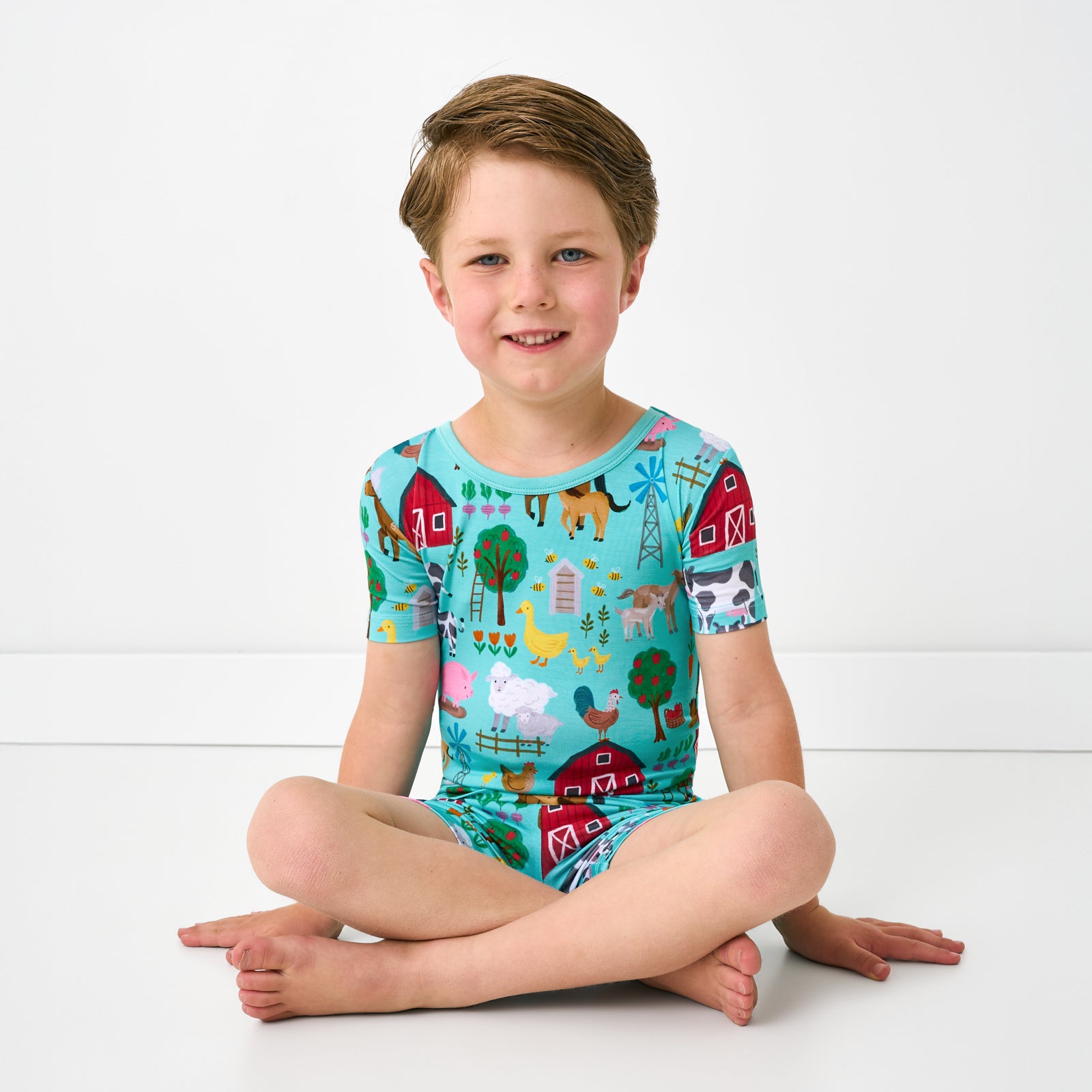 Sitting child wearing the Turquoise Farm Fam Two-Piece Short Sleeve & Shorts Pajama Set