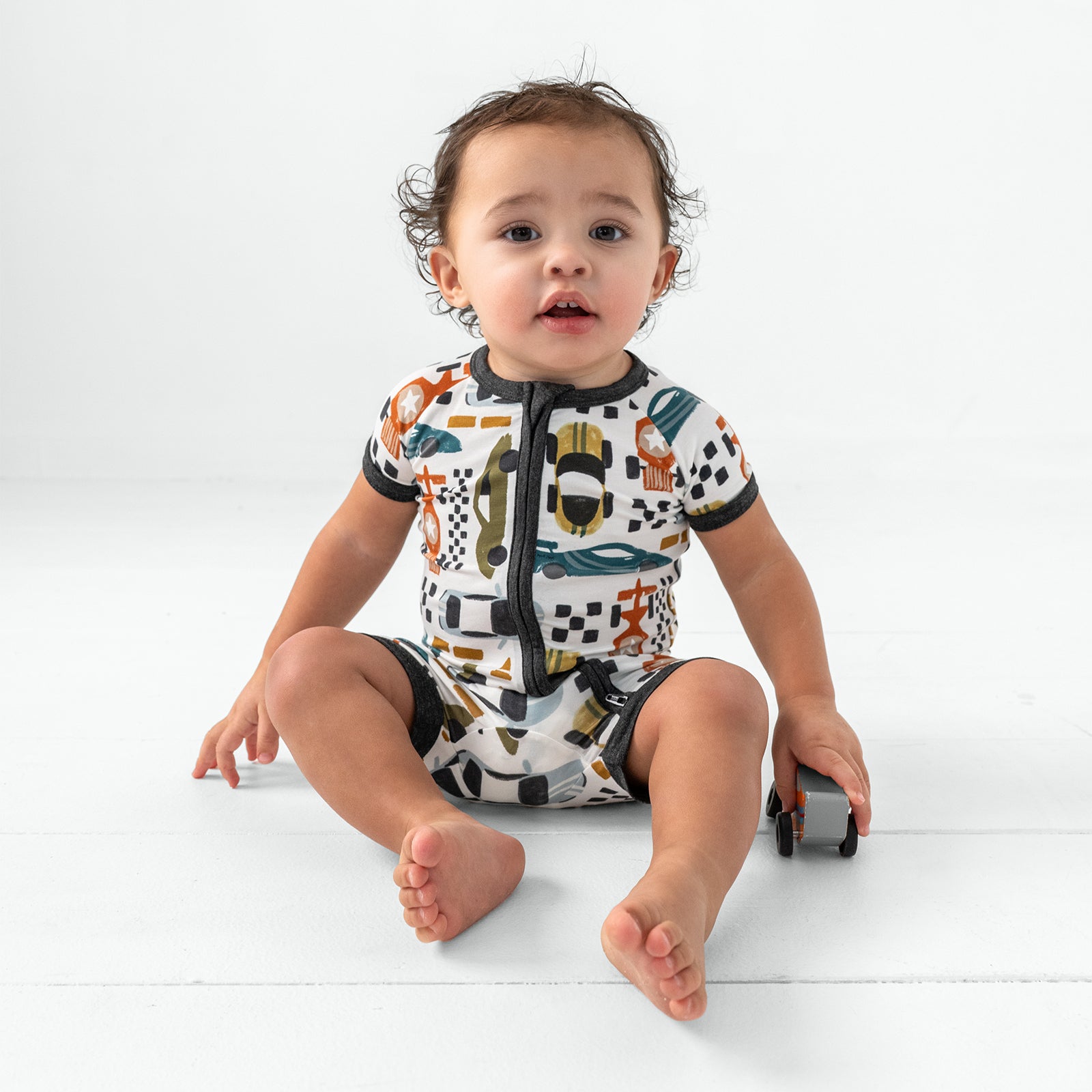 Sitting child wearing the Fast Lane Shorty Zippy playing with a race car toy