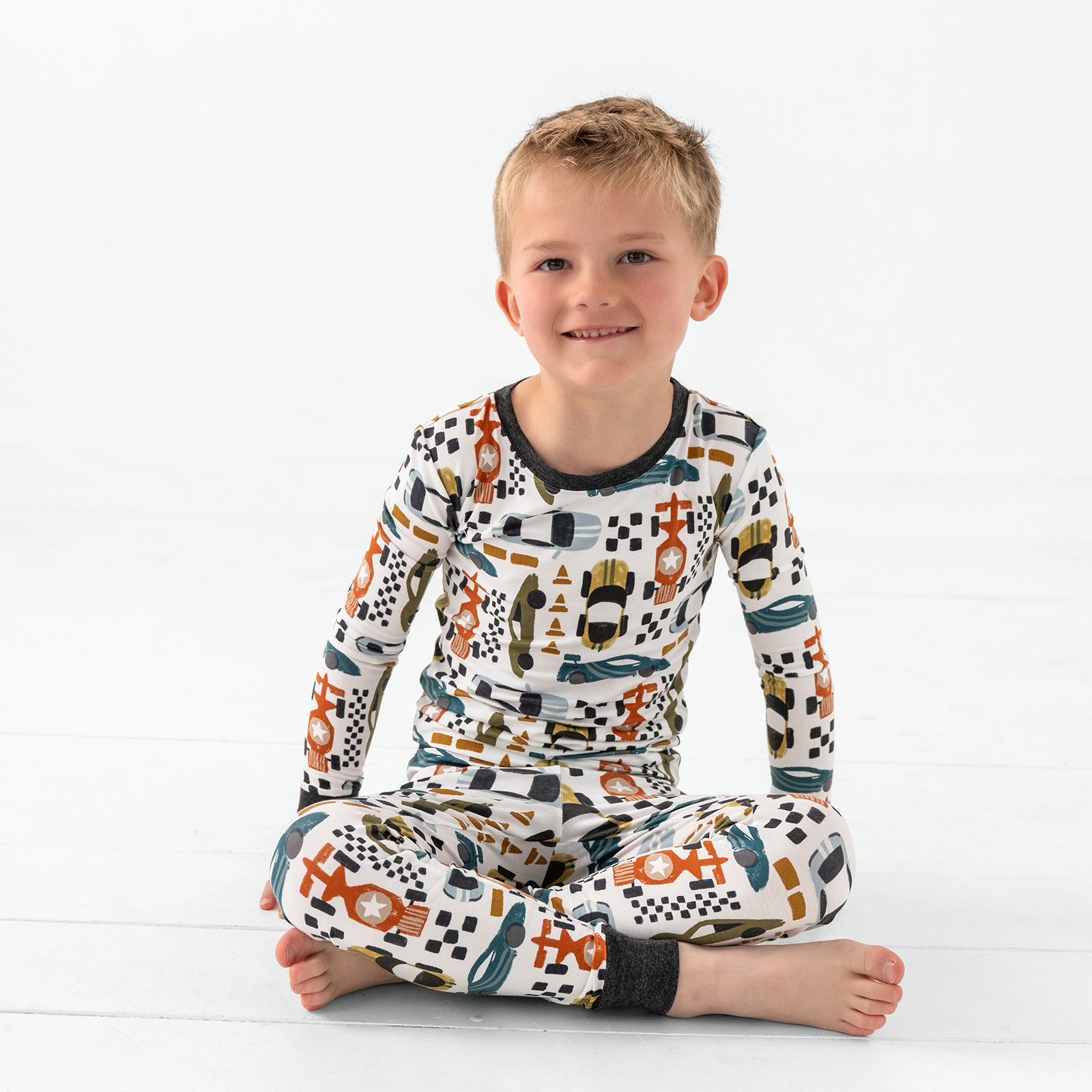 Sitting boy wearing the Fast Lane Two-Piece Pajama Set