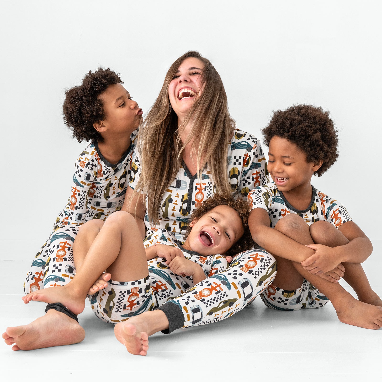 Sitting family of four wearing matching Fast Lane bamboo pajamas