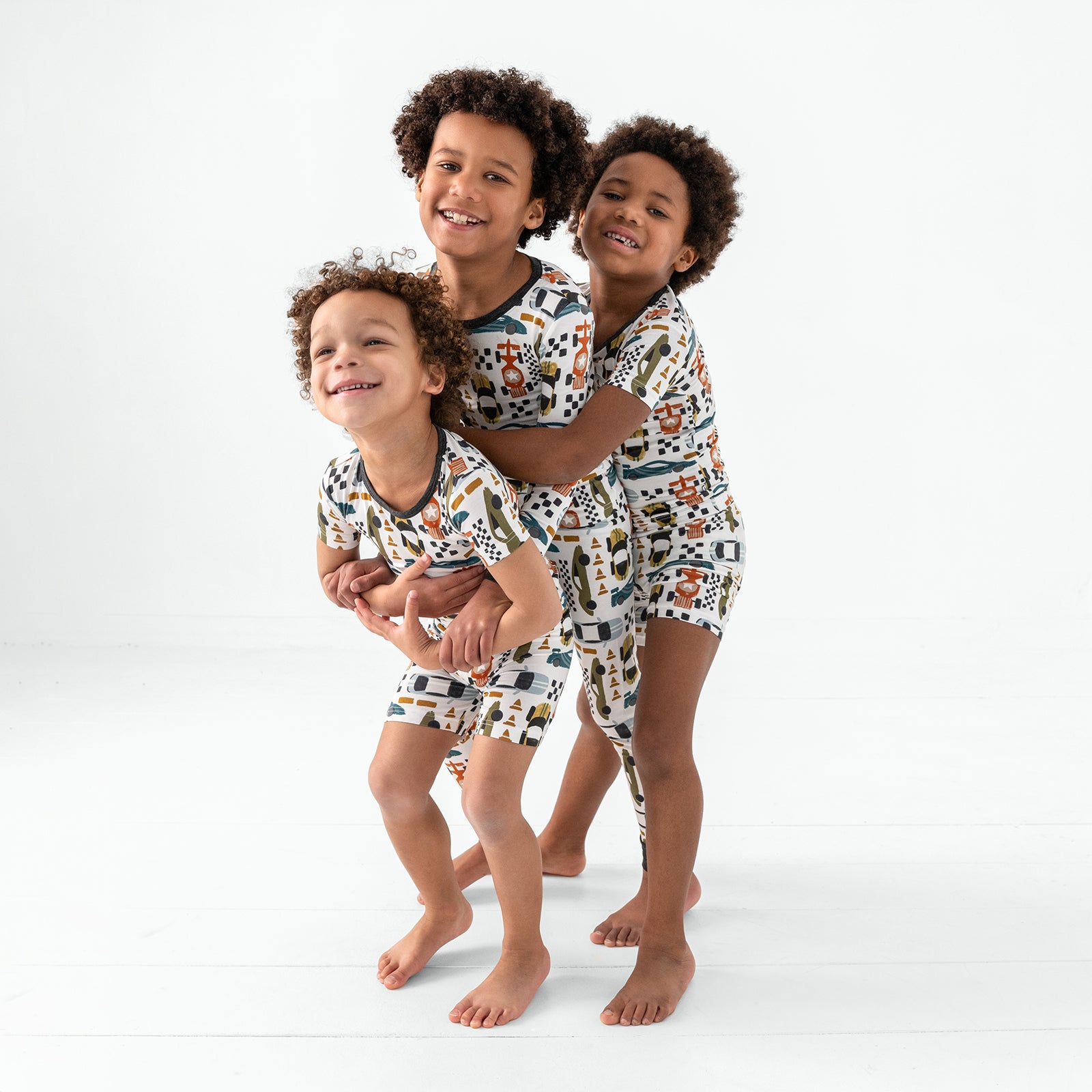 Three children wearing matching Fast Lane Two-Piece Bamboo Pajama Sets
