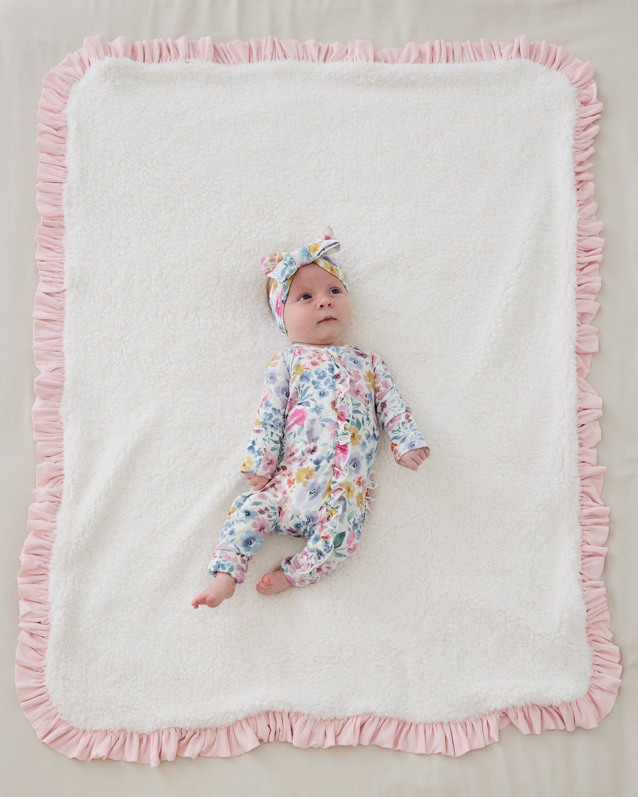 Aerial view of newborn laying on the sherpa side of the Prima Pink Ribbed Ruffle Mini Cloud Blanket®