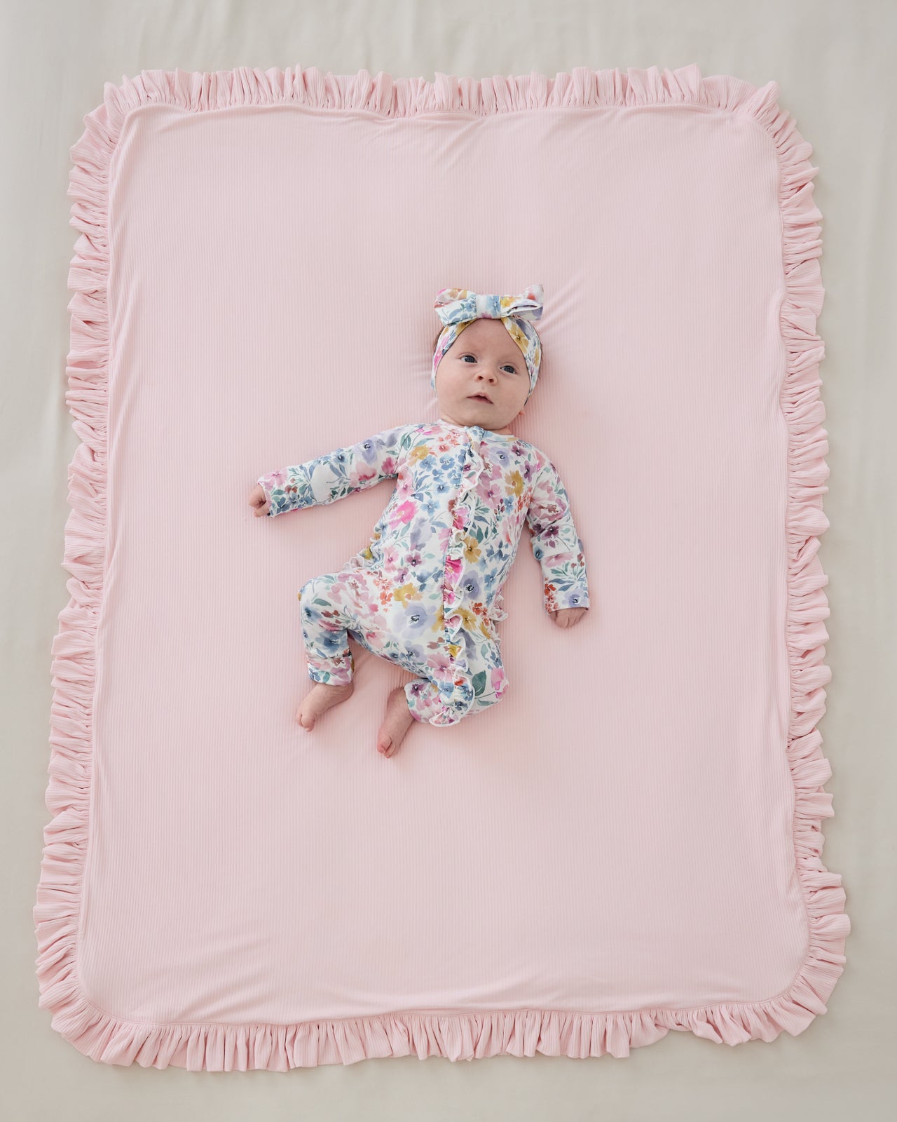 Aerial view of baby laying on the pink side the Prima Pink Ribbed Ruffle Mini Cloud Blanket®