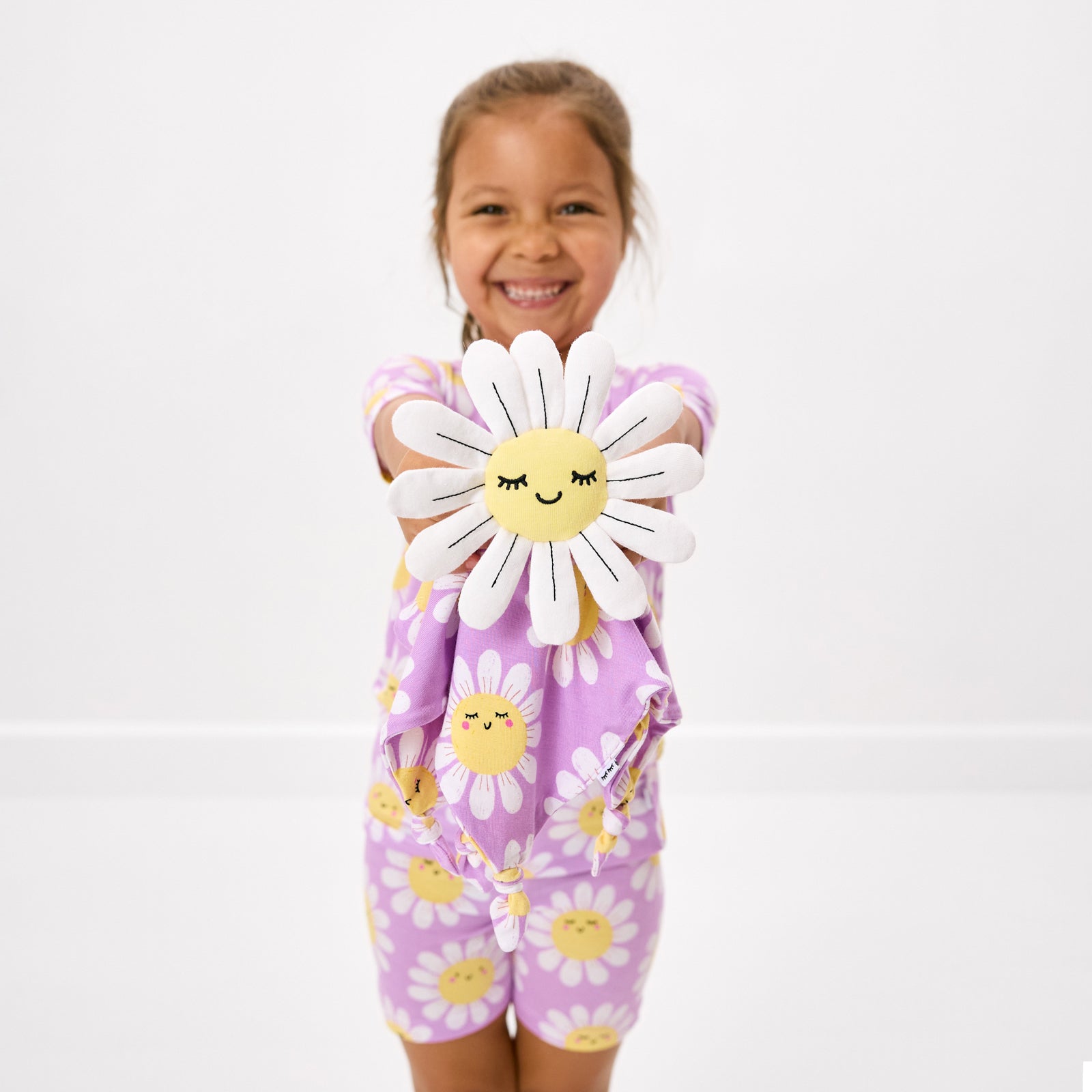 Child holding up the Maisie the Daisy Sleepyhead Lovey