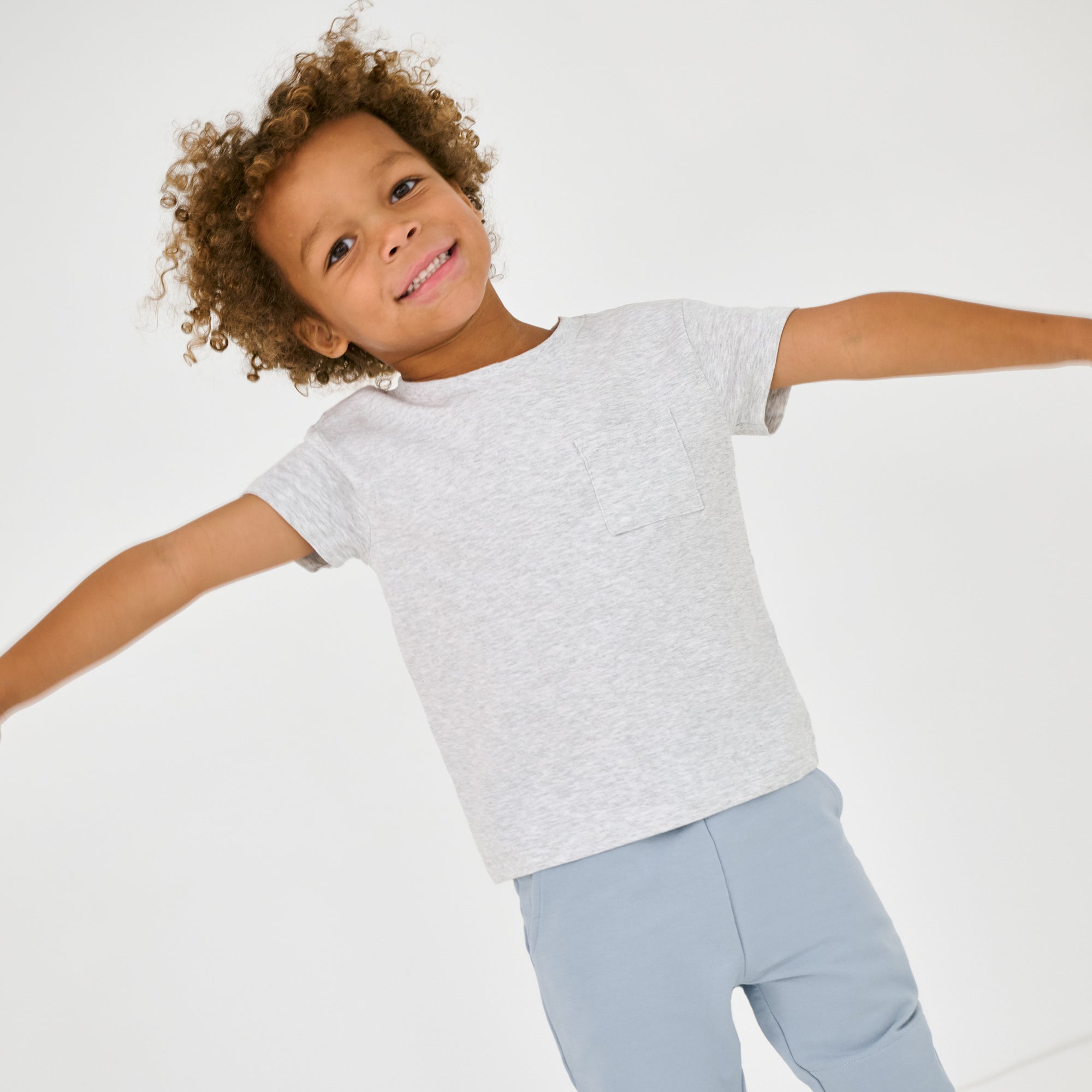 Posing child wearing the Light Heather Gray Relaxed Pocket Tee with Fog Blue jogger sweatpants